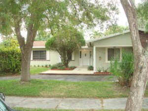 A quaint single-story home with lush greenery and a wooden deck.