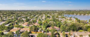Aerial view of a suburban neighborhood with houses and greenery under a blue sky.