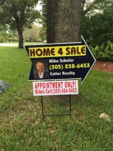 Real estate sign advertising a home for sale with contact info for the realtor.