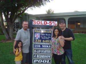 Family celebrating home sale with a 5% discount sign.