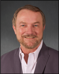 Smiling man in a suit jacket.