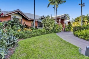 A charming suburban house with a lush front lawn and tropical plants.