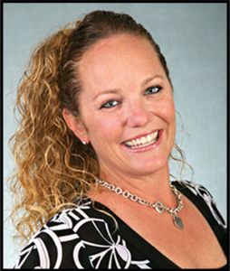 Smiling woman with curly hair and a patterned top.